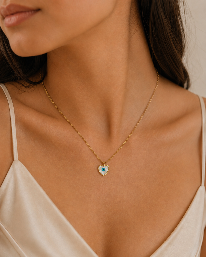 Blue Eye White Heart Necklace featuring a white heart pendant with a blue evil eye centerpiece in a gold finish