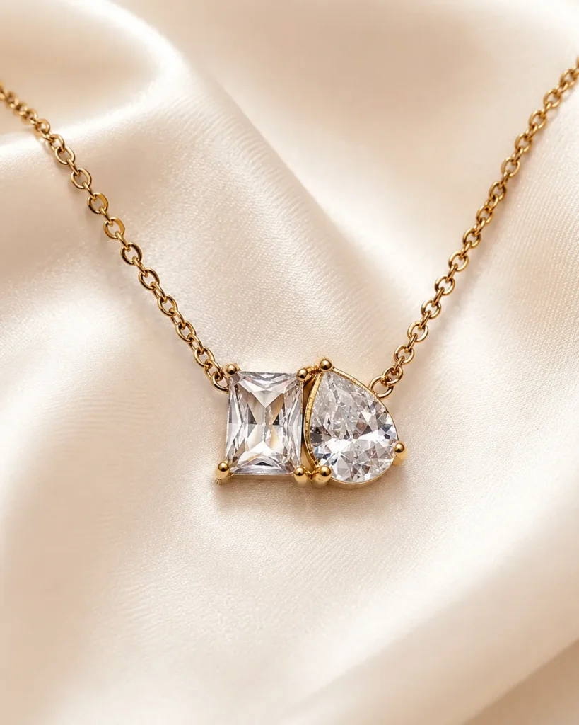 Celeste Twin Stone Necklace featuring emerald-cut and pear-cut clear crystal pendant in a gold setting